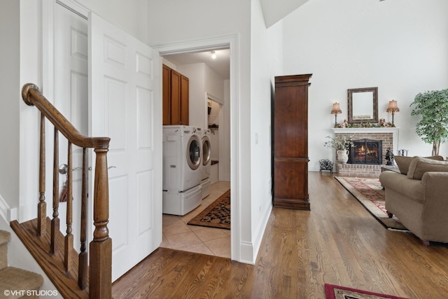 clothes washing area featuring cabinet space, independent washer and dryer, a fireplace, and wood finished floors