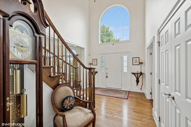 entryway with stairway, baseboards, wood finished floors, and a towering ceiling