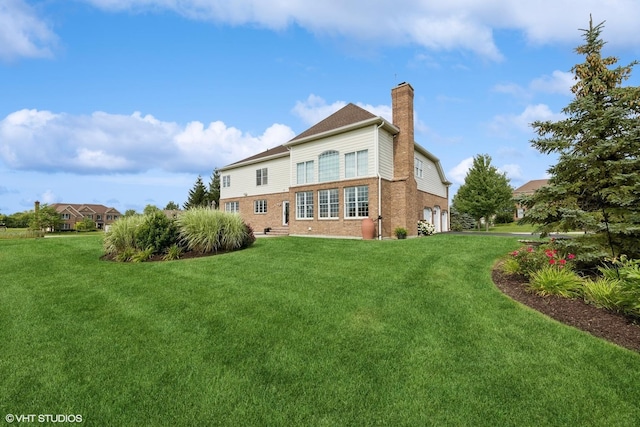 back of house with brick siding, a garage, a lawn, and a chimney