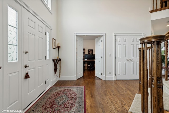 entryway featuring dark wood finished floors, a high ceiling, and baseboards