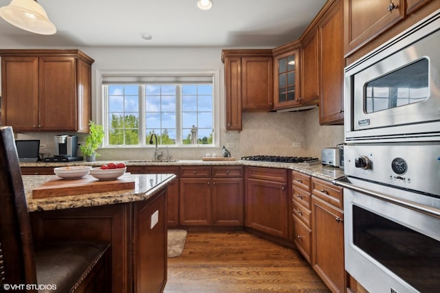 kitchen featuring a sink, decorative backsplash, brown cabinets, and stainless steel appliances