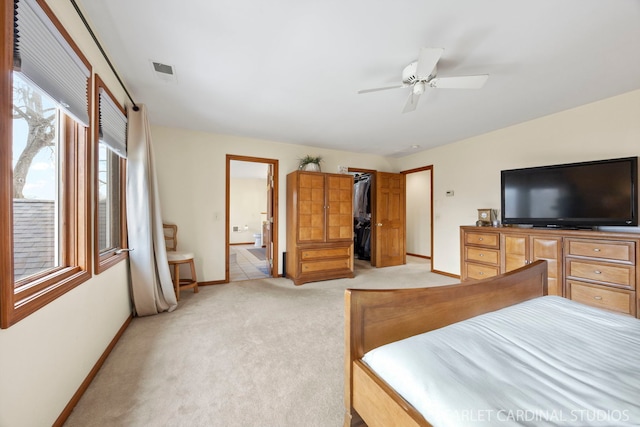 bedroom with visible vents, connected bathroom, baseboards, light colored carpet, and a spacious closet