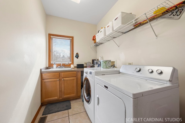 washroom featuring visible vents, washing machine and dryer, light tile patterned flooring, cabinet space, and a sink