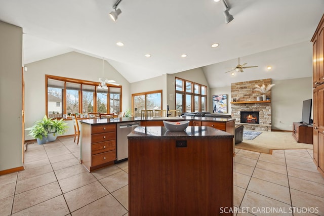 kitchen with a center island, ceiling fan, open floor plan, a stone fireplace, and stainless steel dishwasher