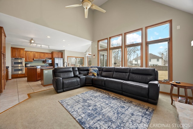 living area with light tile patterned floors, high vaulted ceiling, light carpet, and a ceiling fan