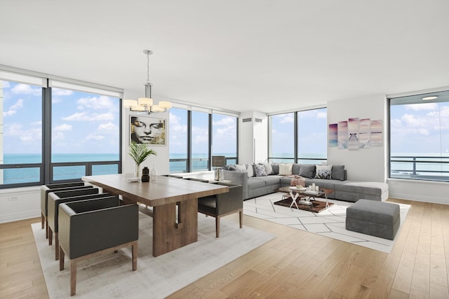 dining area featuring a chandelier, baseboards, light wood-style floors, and a water view