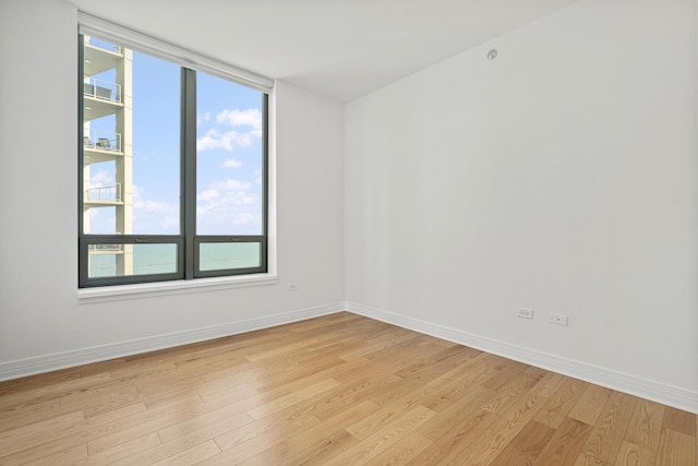 spare room featuring baseboards and light wood-type flooring