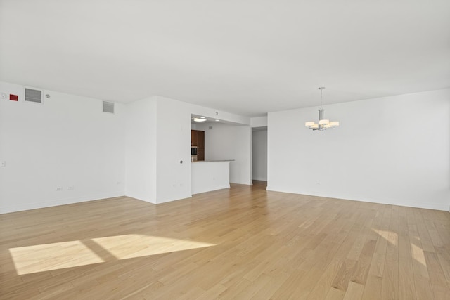 unfurnished room featuring light wood-type flooring, visible vents, baseboards, and an inviting chandelier