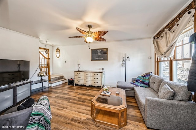 living area with stairway, wood finished floors, a ceiling fan, and crown molding