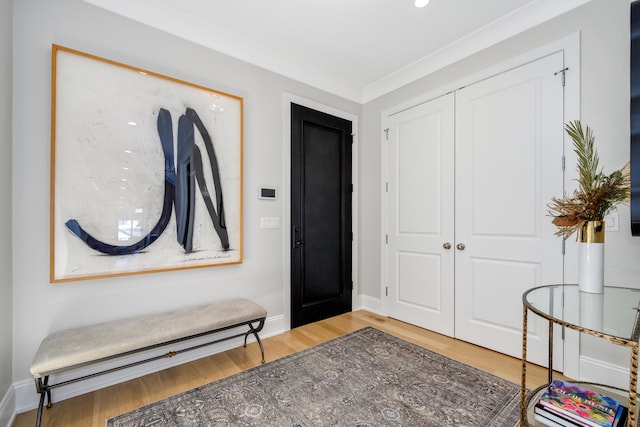 entryway featuring crown molding, baseboards, and light wood finished floors