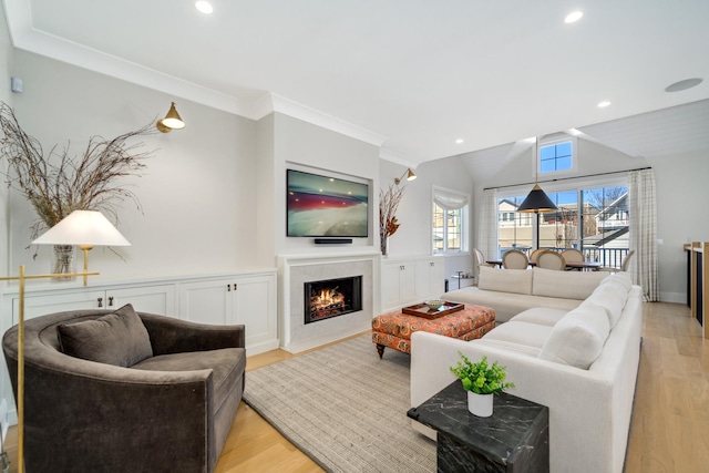 living area with vaulted ceiling, recessed lighting, light wood-style floors, and a premium fireplace