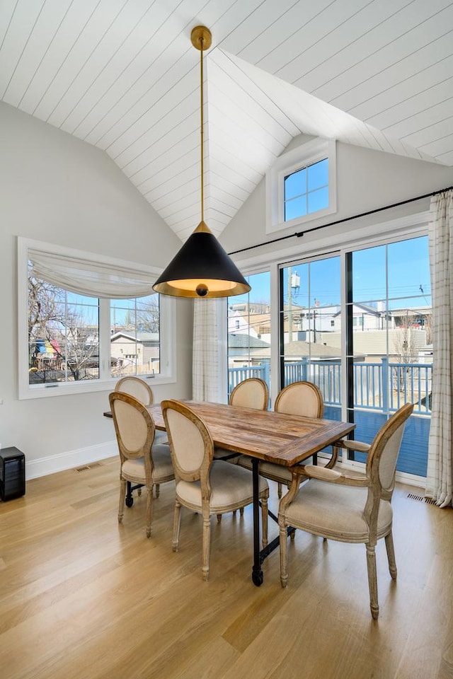 dining room featuring plenty of natural light, light wood-style flooring, and vaulted ceiling