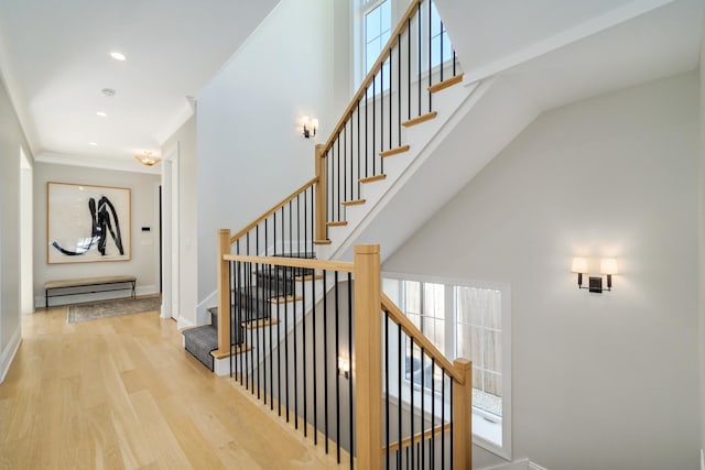 stairs with baseboards, ornamental molding, recessed lighting, a high ceiling, and wood finished floors