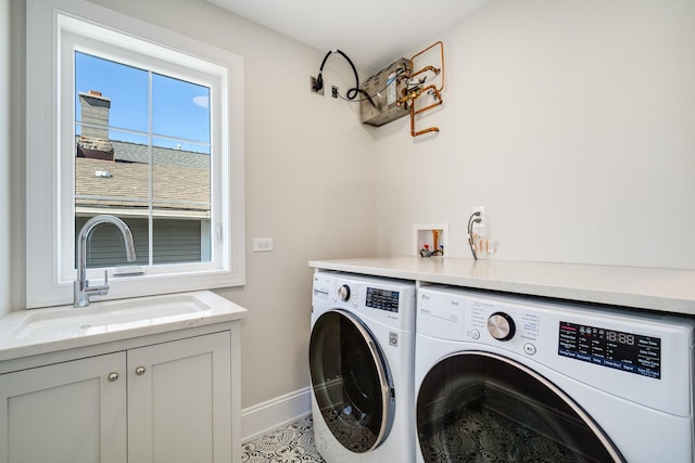 clothes washing area featuring a sink, baseboards, cabinet space, and washer and dryer