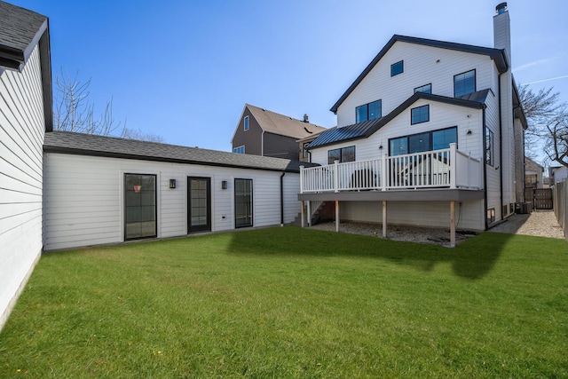 back of property with a deck, a chimney, a yard, and fence