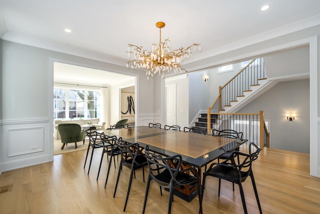 dining room featuring stairway, recessed lighting, wainscoting, light wood-style floors, and a decorative wall