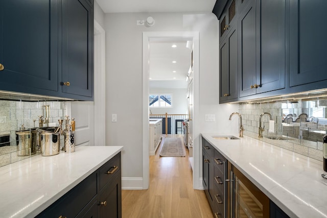 bar with recessed lighting, backsplash, light wood-style floors, and a sink