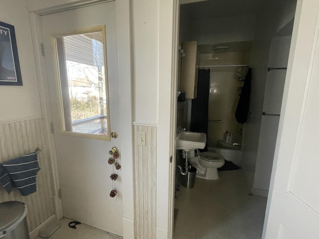 bathroom with toilet, washtub / shower combination, and a wainscoted wall