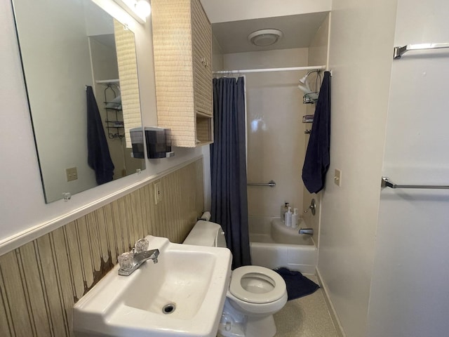 bathroom with shower / tub combo, toilet, baseboards, and a sink