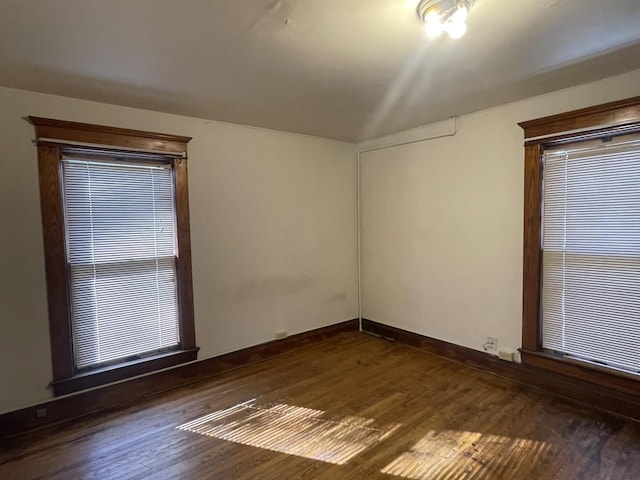 spare room featuring baseboards and dark wood-style floors