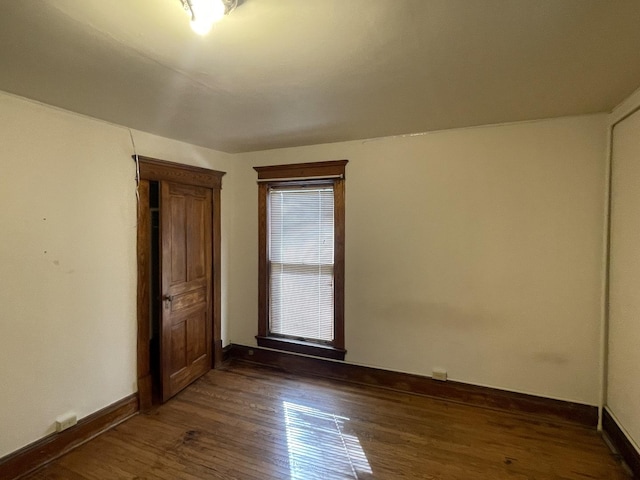 empty room with baseboards and dark wood-style floors