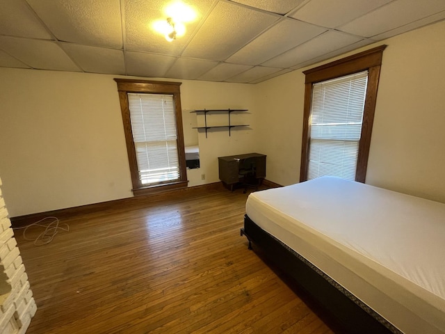 bedroom featuring baseboards, a paneled ceiling, and hardwood / wood-style flooring