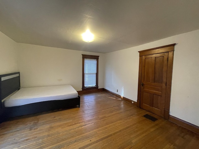 unfurnished bedroom with visible vents, baseboards, and hardwood / wood-style flooring