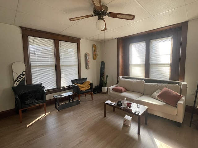 living room featuring ceiling fan, baseboards, a paneled ceiling, and wood finished floors