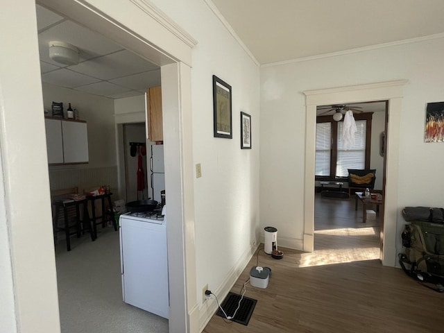 hall with wood finished floors, visible vents, baseboards, washer / clothes dryer, and crown molding