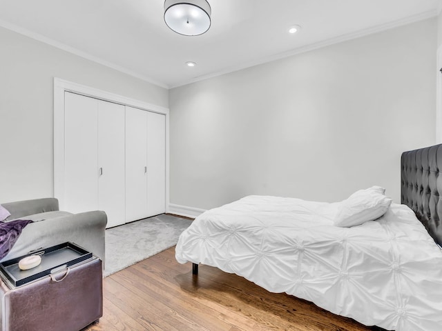 bedroom with a closet, recessed lighting, wood finished floors, and ornamental molding