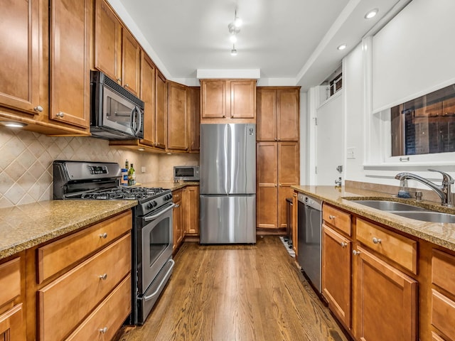 kitchen with dark wood-style flooring, brown cabinets, appliances with stainless steel finishes, and a sink