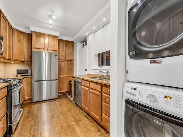 kitchen featuring a sink, brown cabinets, stacked washer / drying machine, and stainless steel appliances