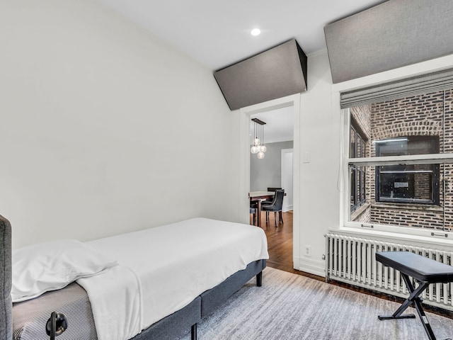 bedroom with wood finished floors, radiator heating unit, recessed lighting, crown molding, and baseboards