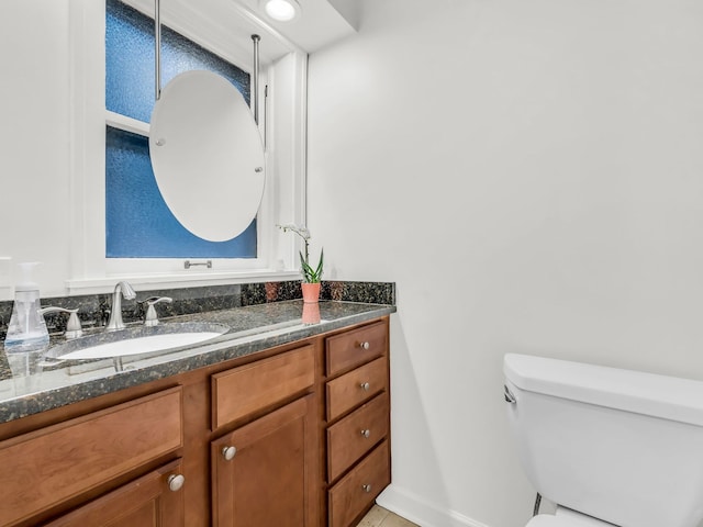 bathroom with baseboards, toilet, and vanity