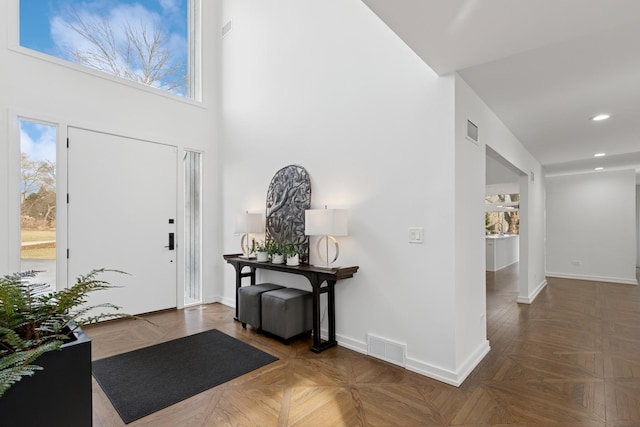 foyer with visible vents, baseboards, a towering ceiling, and recessed lighting