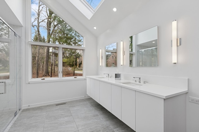 bathroom featuring a stall shower, visible vents, a skylight, and a sink