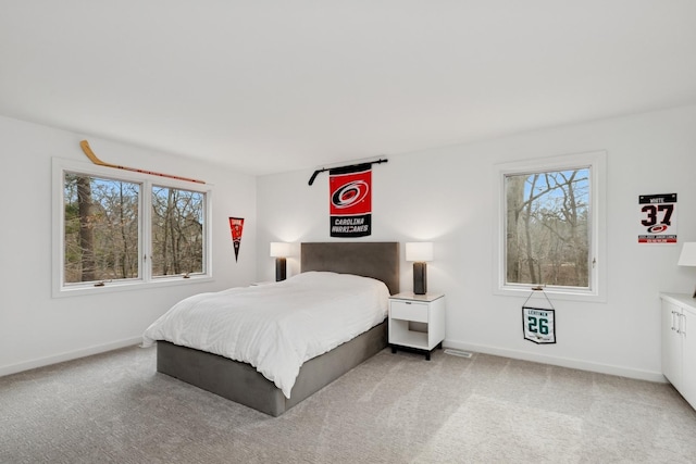 bedroom featuring baseboards, multiple windows, and light colored carpet