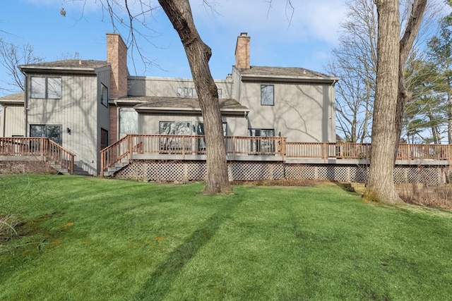 rear view of property featuring a lawn, a chimney, and a deck