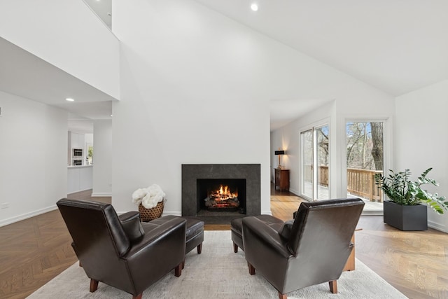 living room with baseboards, high vaulted ceiling, a high end fireplace, and recessed lighting
