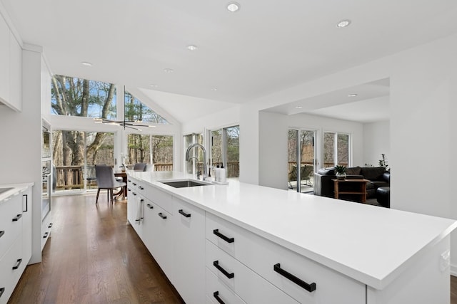 kitchen featuring light countertops, recessed lighting, dark wood-type flooring, lofted ceiling, and a sink