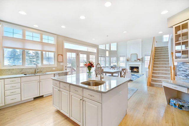 kitchen featuring light wood finished floors, plenty of natural light, a lit fireplace, and a sink