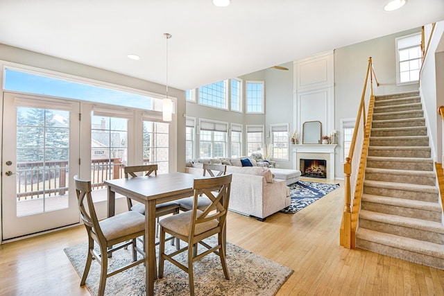 dining room featuring stairway, recessed lighting, light wood-style floors, and a lit fireplace