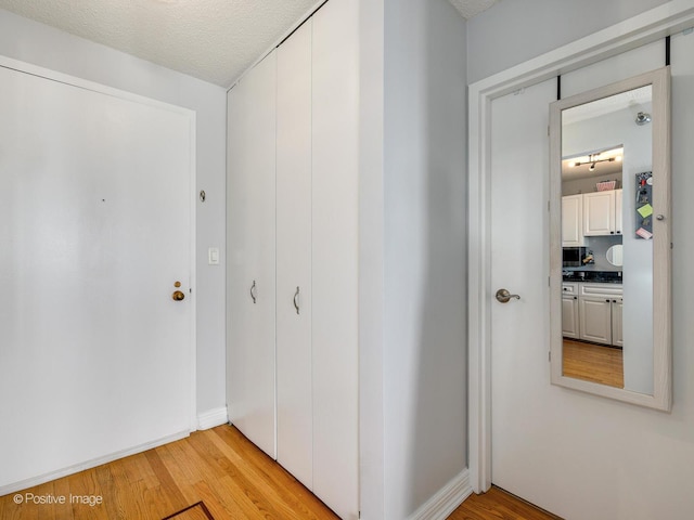 hall featuring light wood-style floors and a textured ceiling