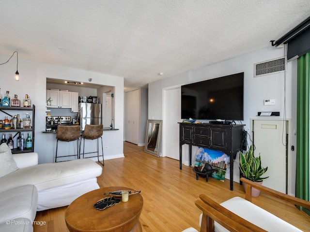 living area with light wood-style flooring, visible vents, and a textured ceiling