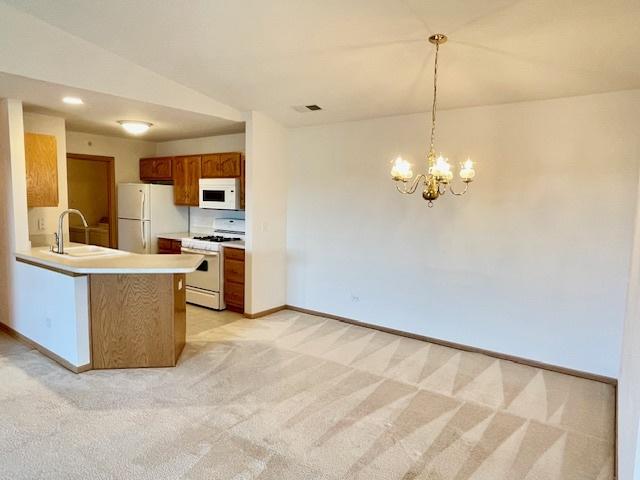 kitchen featuring a sink, visible vents, white appliances, and light colored carpet