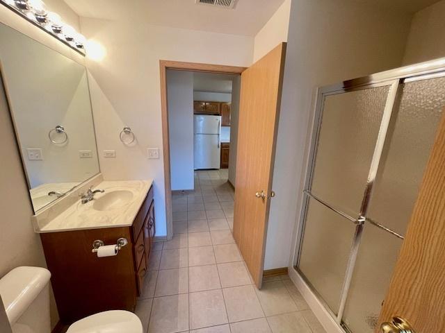 full bathroom featuring vanity, visible vents, tile patterned flooring, a shower stall, and toilet