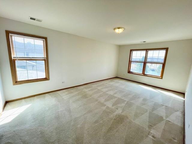 unfurnished room featuring baseboards, light carpet, and visible vents