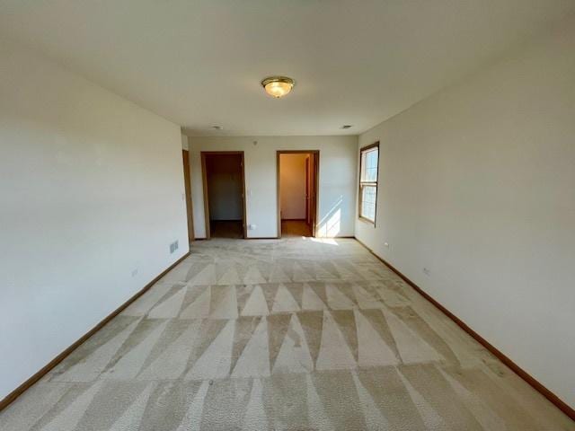 empty room featuring light colored carpet and baseboards