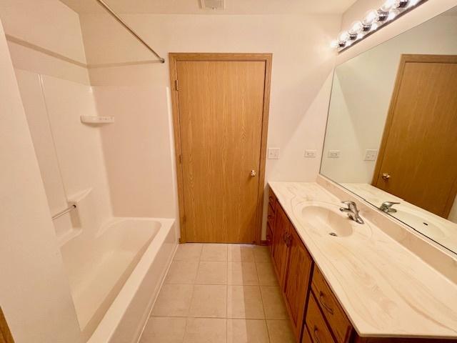 bathroom with bathing tub / shower combination, vanity, and tile patterned flooring