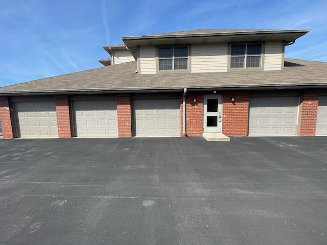 view of front of house with brick siding, a shingled roof, and a garage